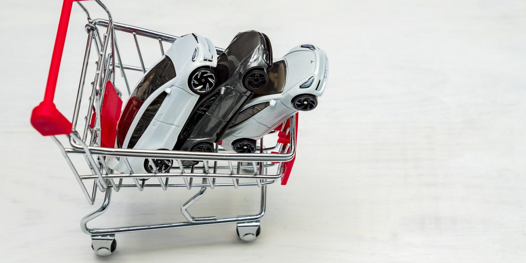 Trolley cart full of toy cars Tesla on a white background