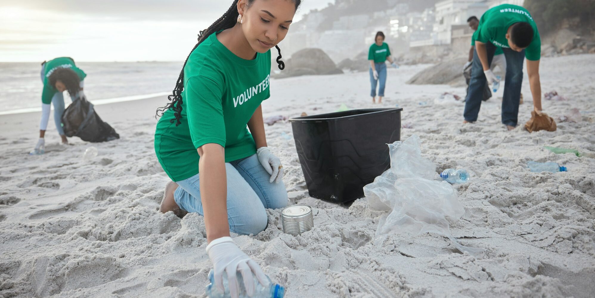 Teamwork, cleaning and recycling with black woman on beach for sustainability, environment and eco