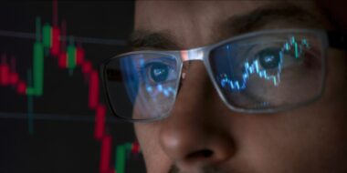 trader wearing glasses, with crypto market charts reflecting on the lenses
