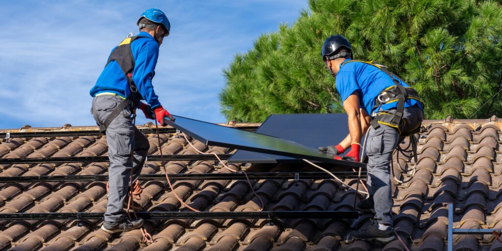 Workers installing solar panel on a roof on a sunny day