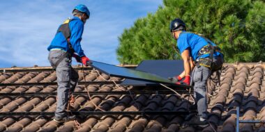 Workers installing solar panel on a roof on a sunny day